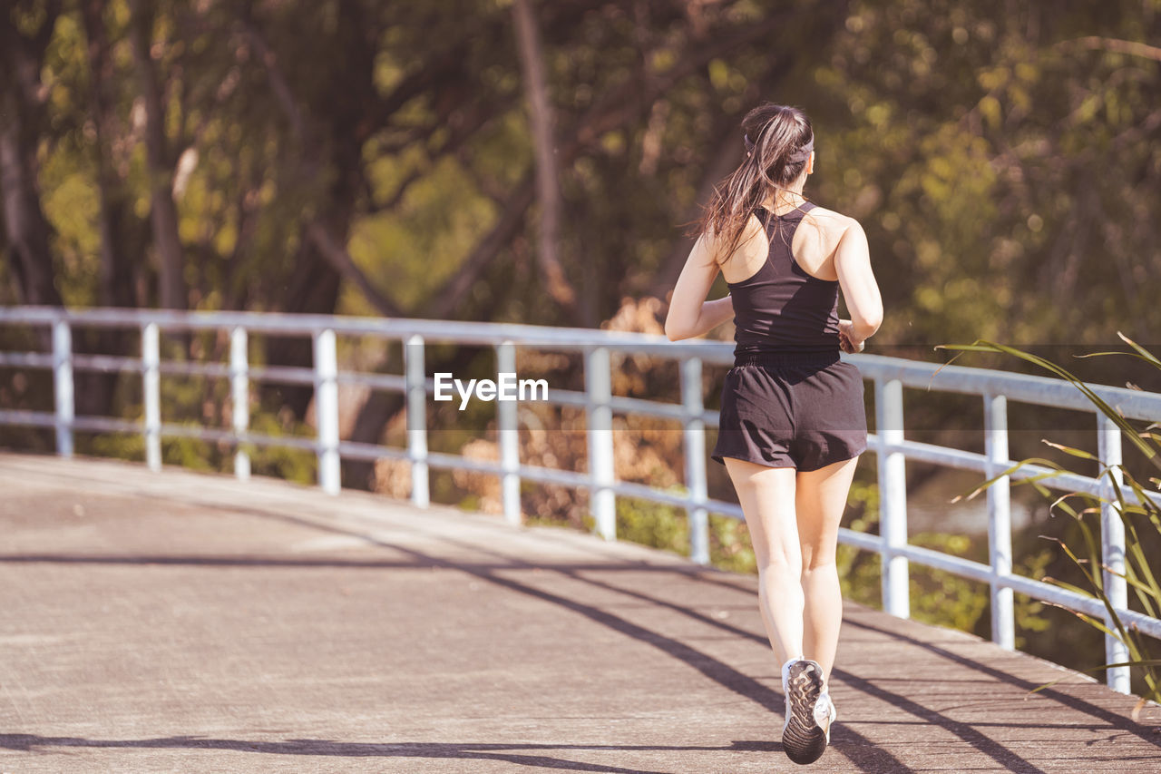 FULL LENGTH OF WOMAN STANDING BY FOOTBRIDGE