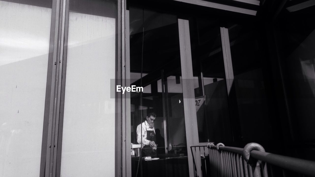 Chef at restaurant seen through glass window