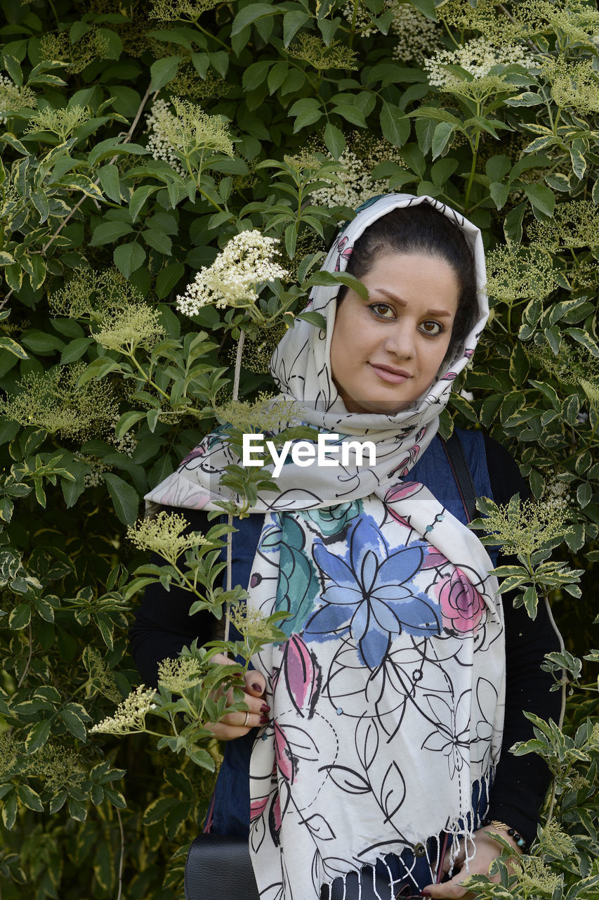 Portrait of smiling woman standing amidst plants