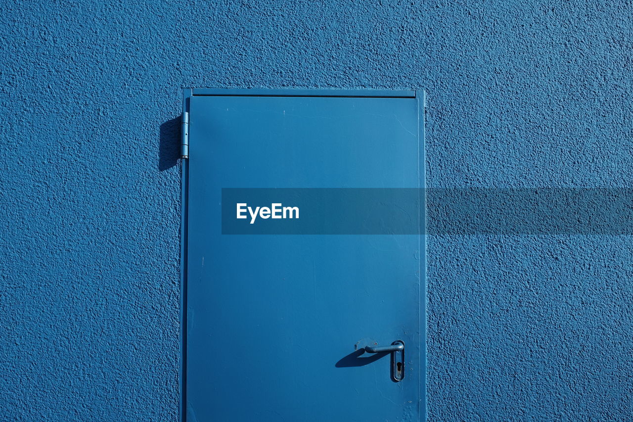 Close-up of closed door on blue wall