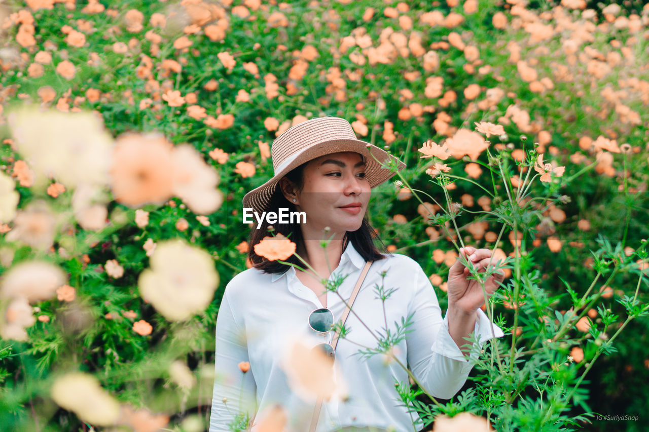 Young woman standing by flowering plants