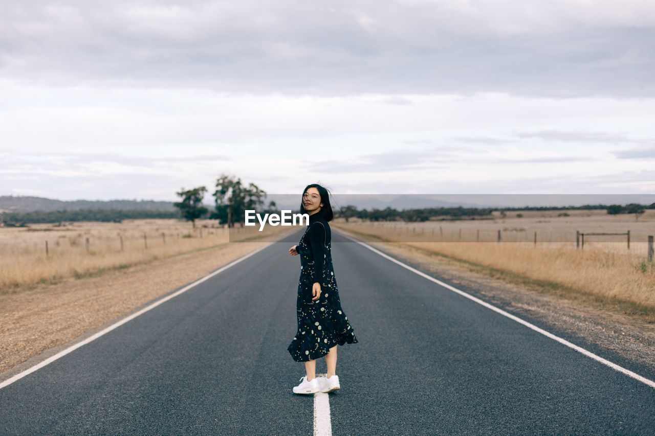 Full length of woman standing on road against sky