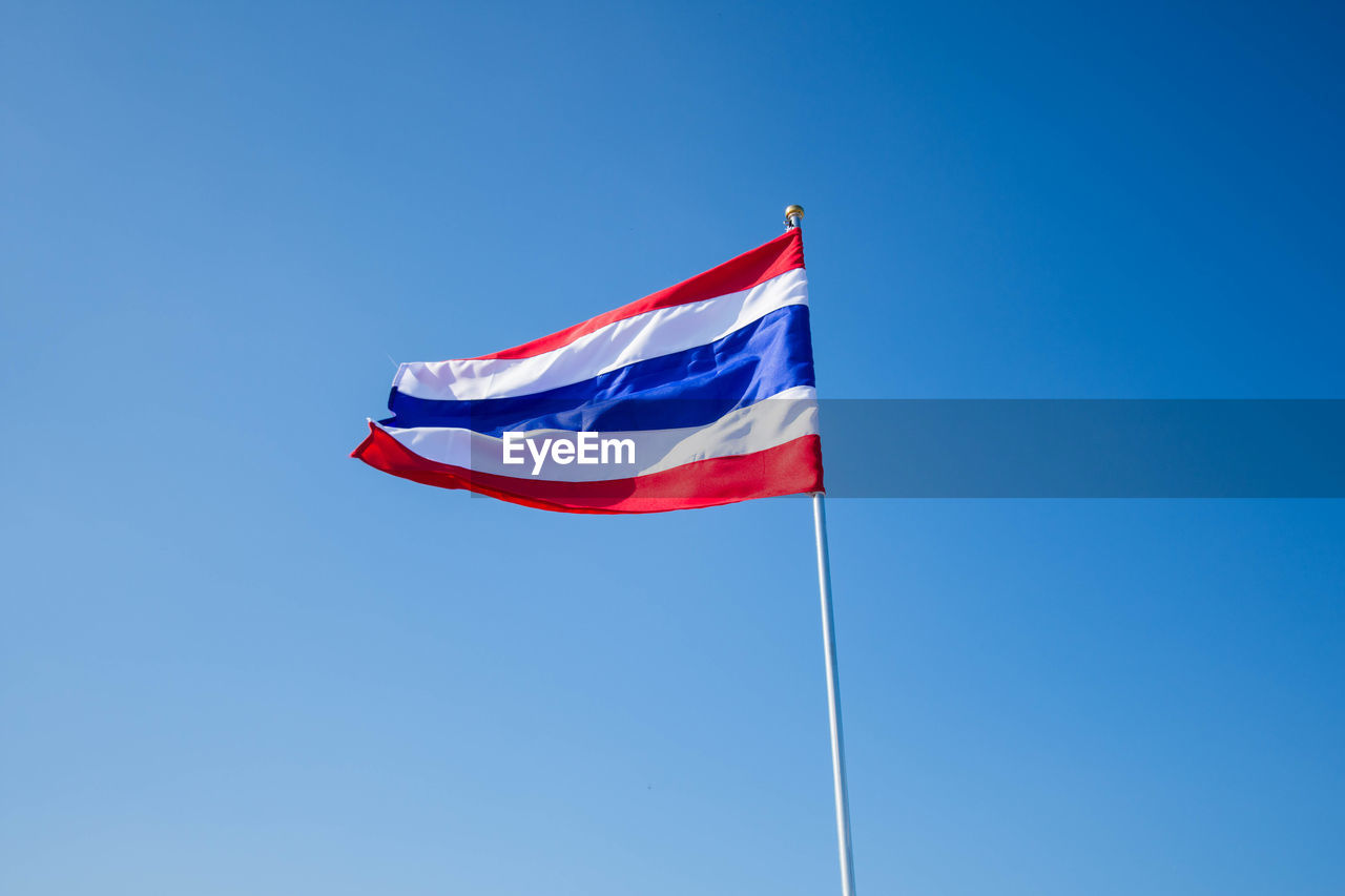 Low angle view of thai flag waving against clear blue sky