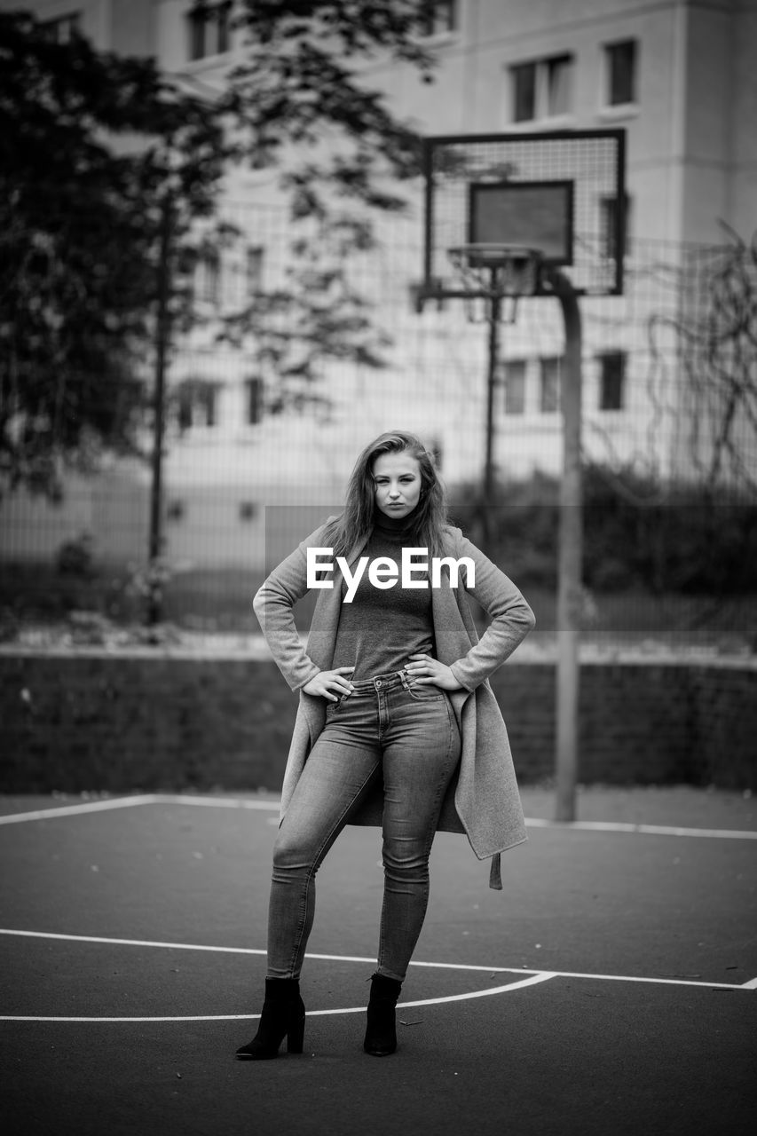 Portrait of young woman standing at basketball court