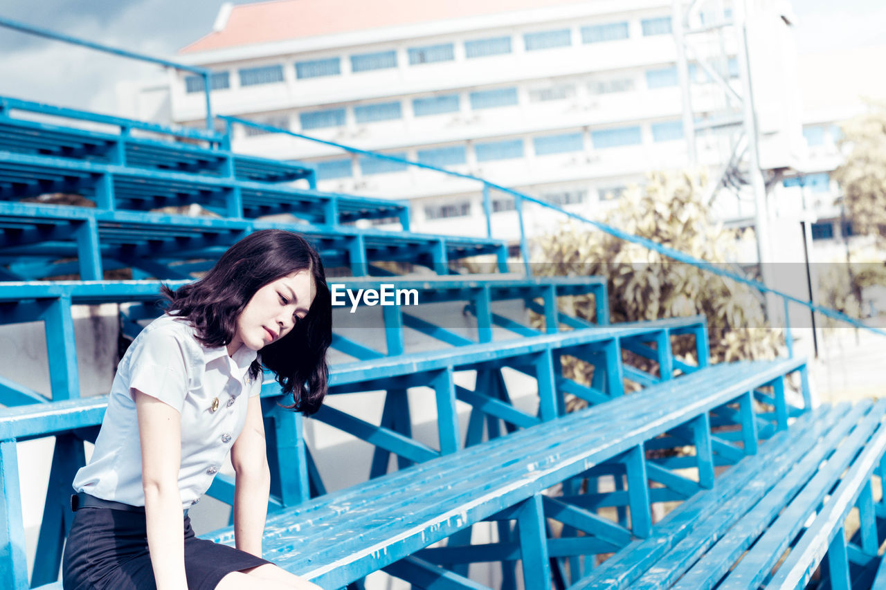 Woman sitting on bleacher