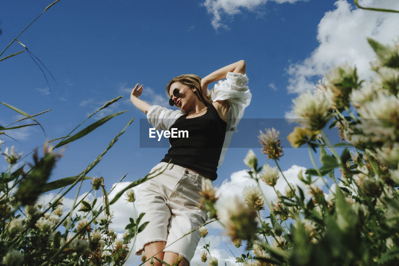 Woman having fun dancing under sky on sunny day