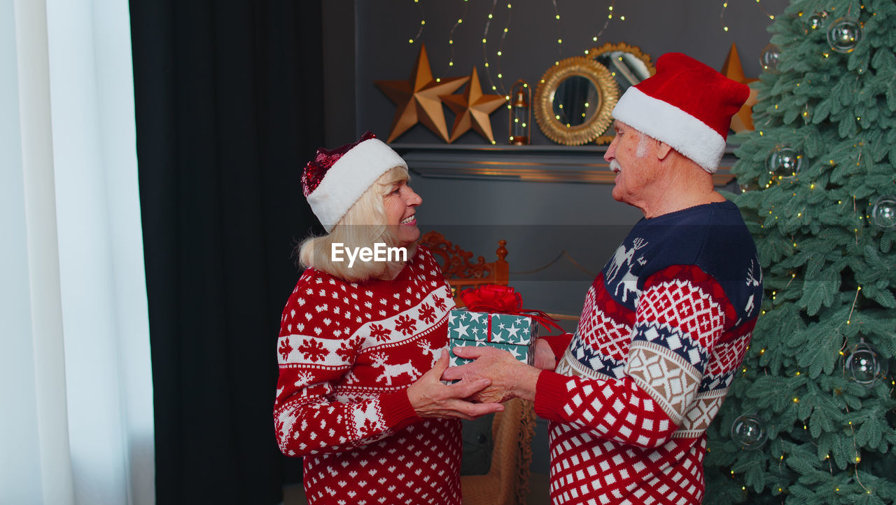 Senior couple wearing santa hat at home