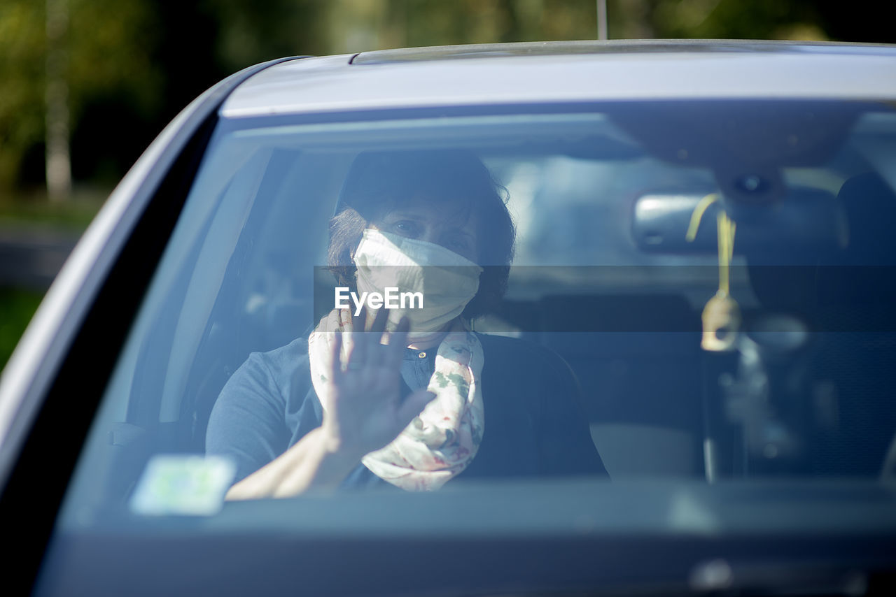 Elderly senior woman wearing a face mask while sitting in car during covid-19 epidemic