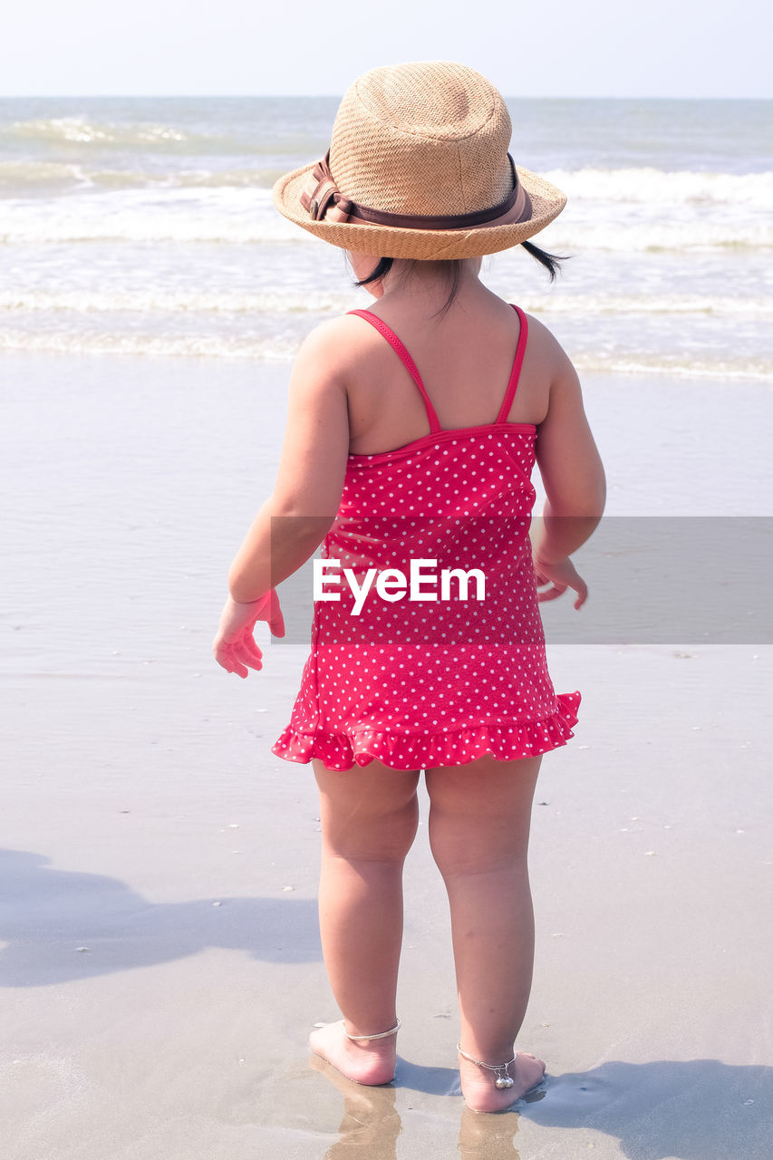 REAR VIEW OF GIRL STANDING ON BEACH