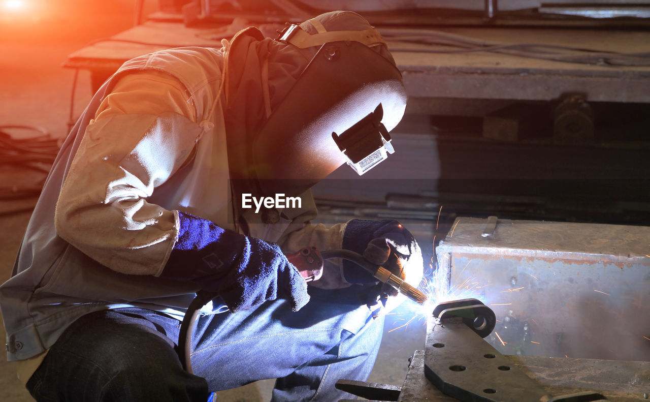 LOW ANGLE VIEW OF MAN WORKING IN METAL MACHINE