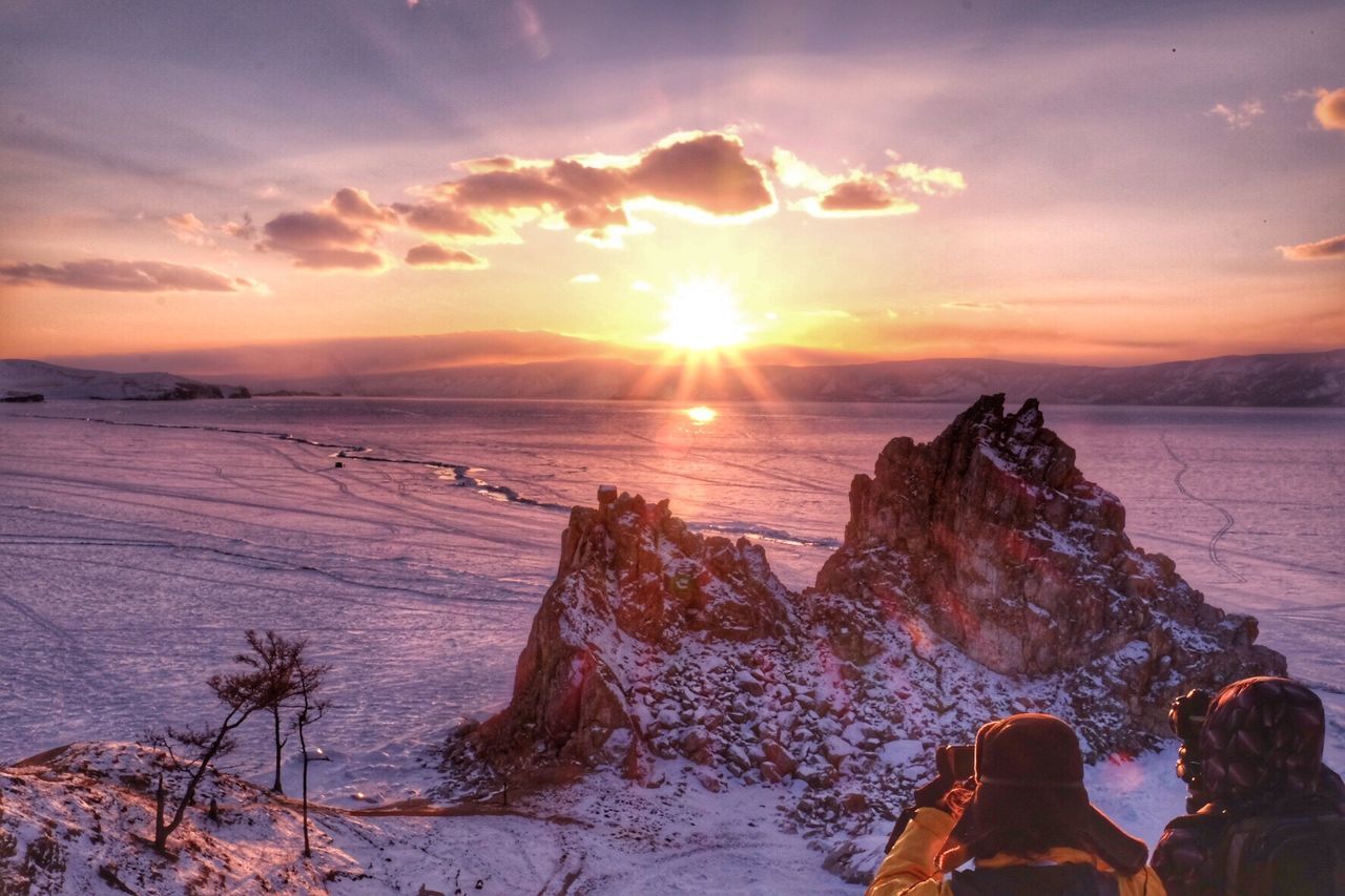 Rear view of people wearing warm clothing while photographing during sunset