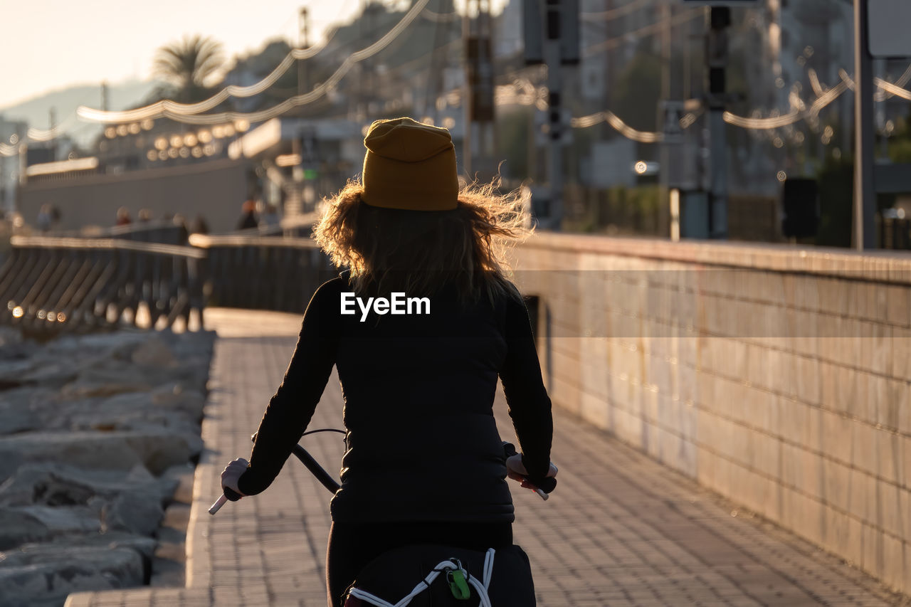 Rear view of woman cycling on footpath