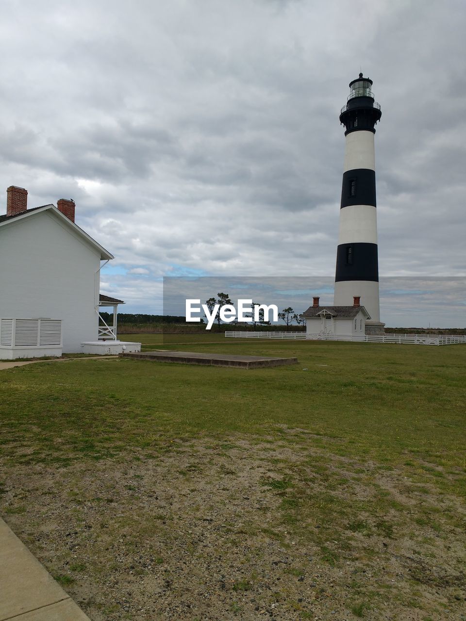 LIGHTHOUSE AMIDST BUILDINGS AGAINST SKY