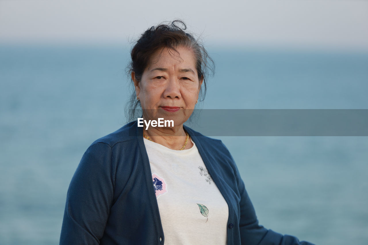 Portrait of senior woman standing against sea