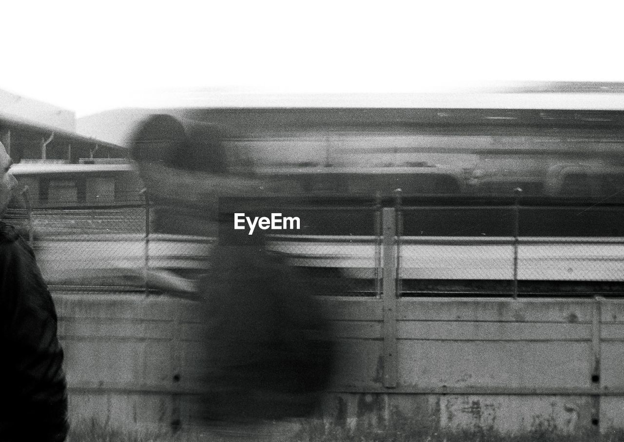 BLURRED MOTION OF TRAIN AGAINST SKY SEEN THROUGH GLASS WINDOW