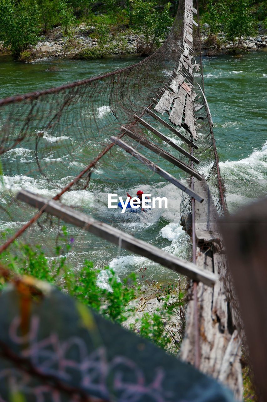 High angle view of man rafting in river seen through broken footbridge