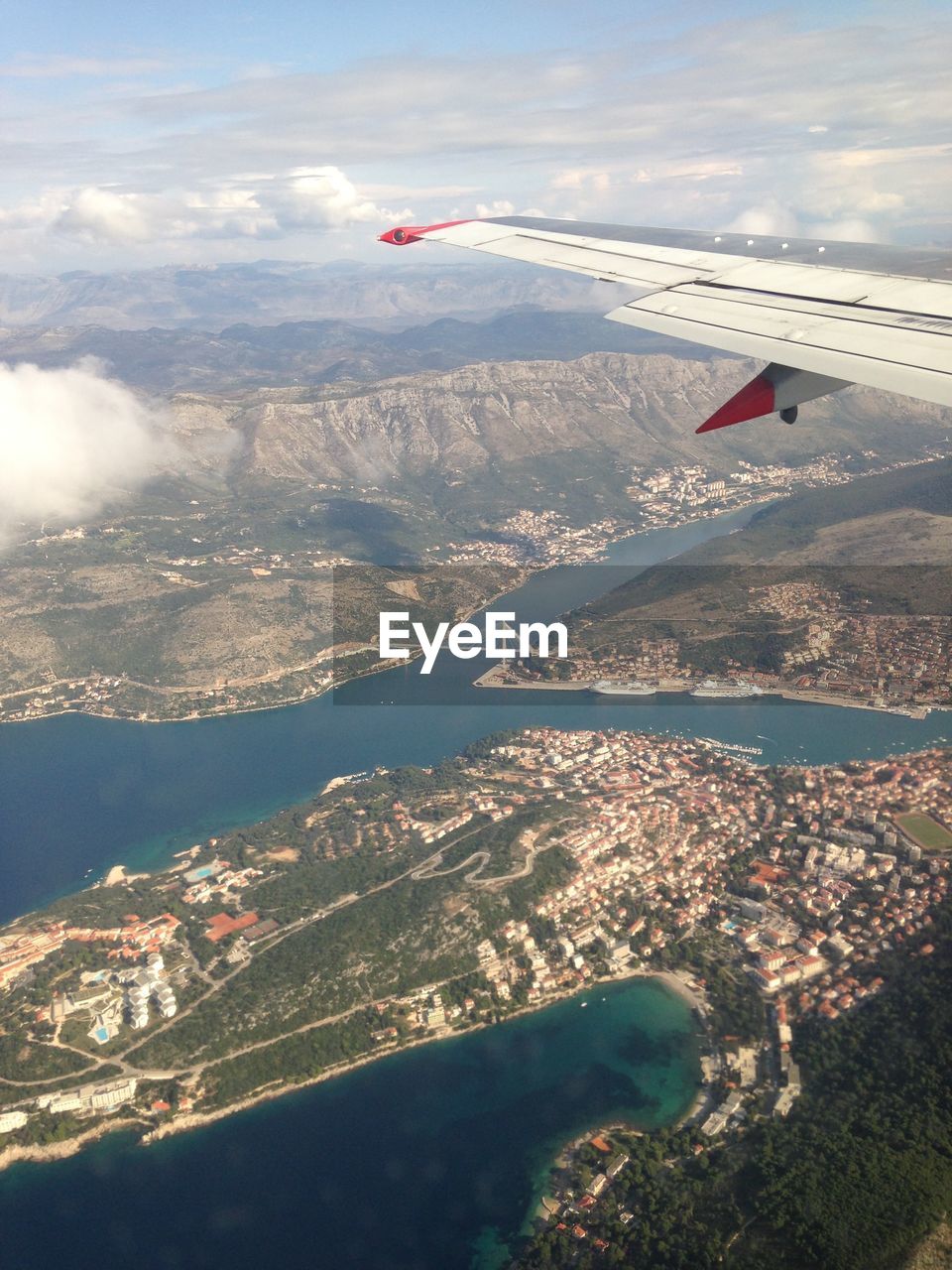 AERIAL VIEW OF AIRPLANE FLYING OVER MOUNTAINS AGAINST SKY