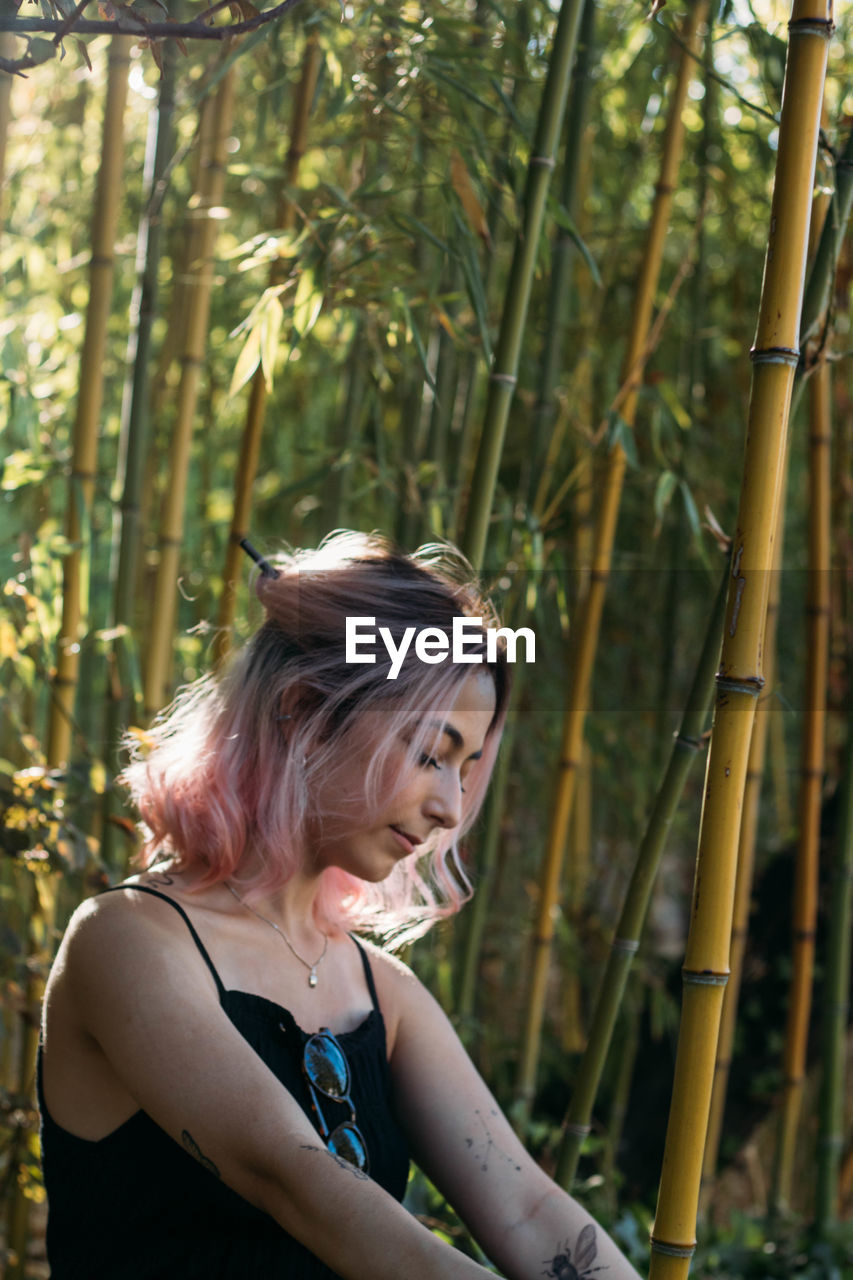 Close-up of young woman with closed eyes sitting in forest