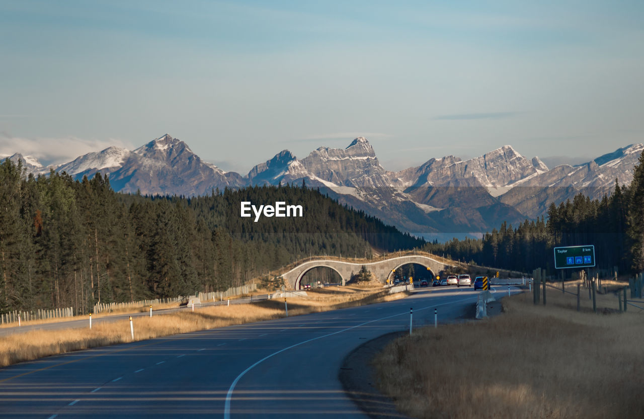 Road leading towards snowcapped mountains against sky