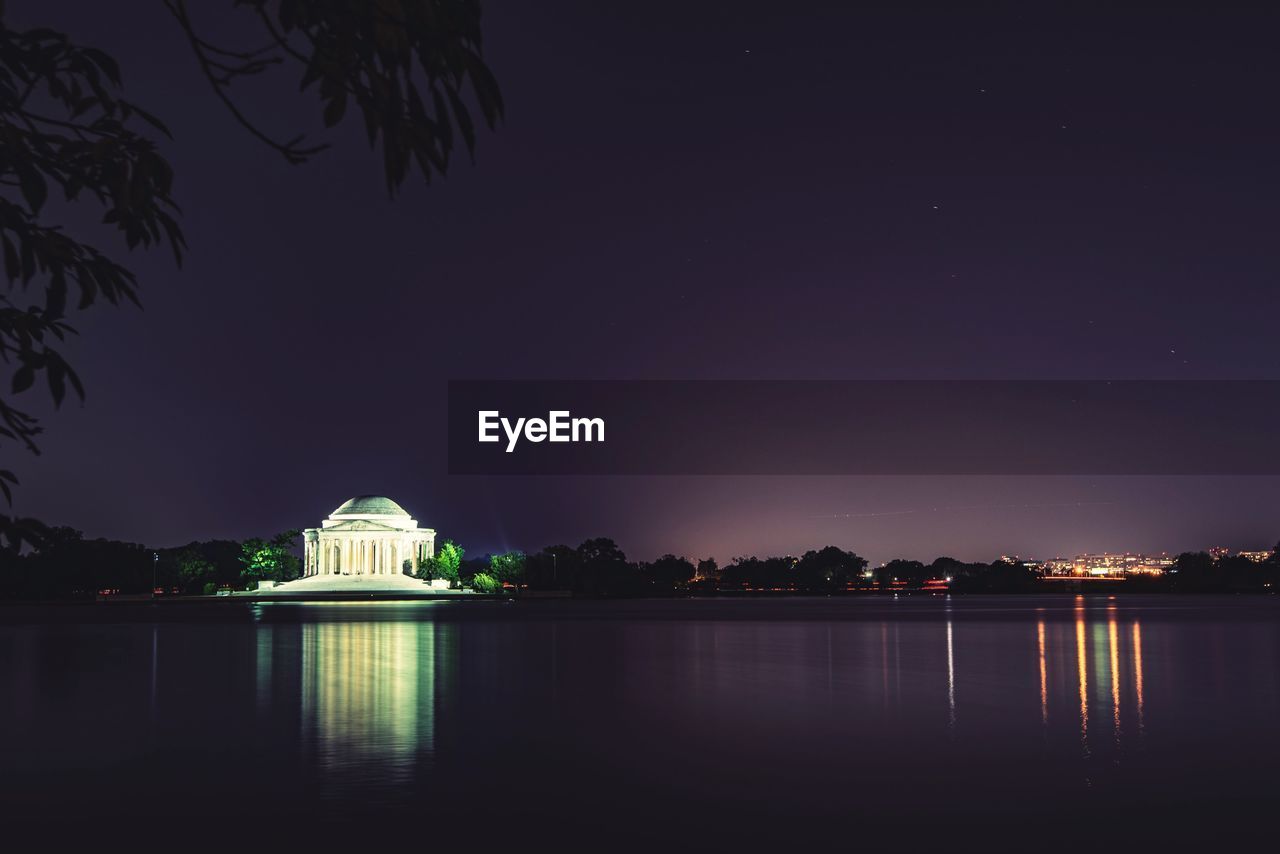 Illuminated building by lake at night