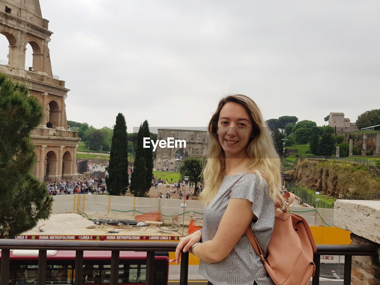 Portrait of smiling young woman standing by coliseum