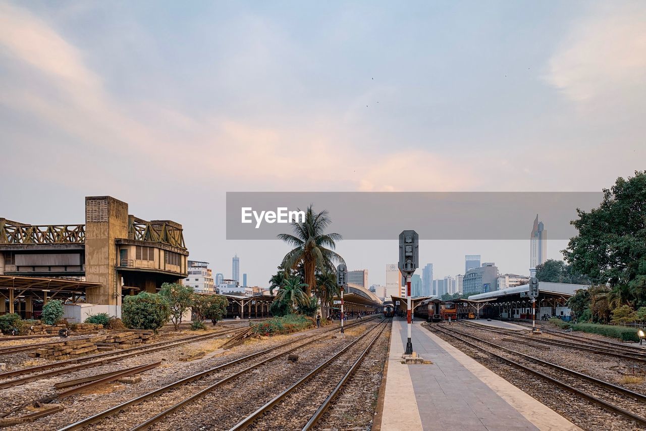 Railroad tracks by buildings in city against sky