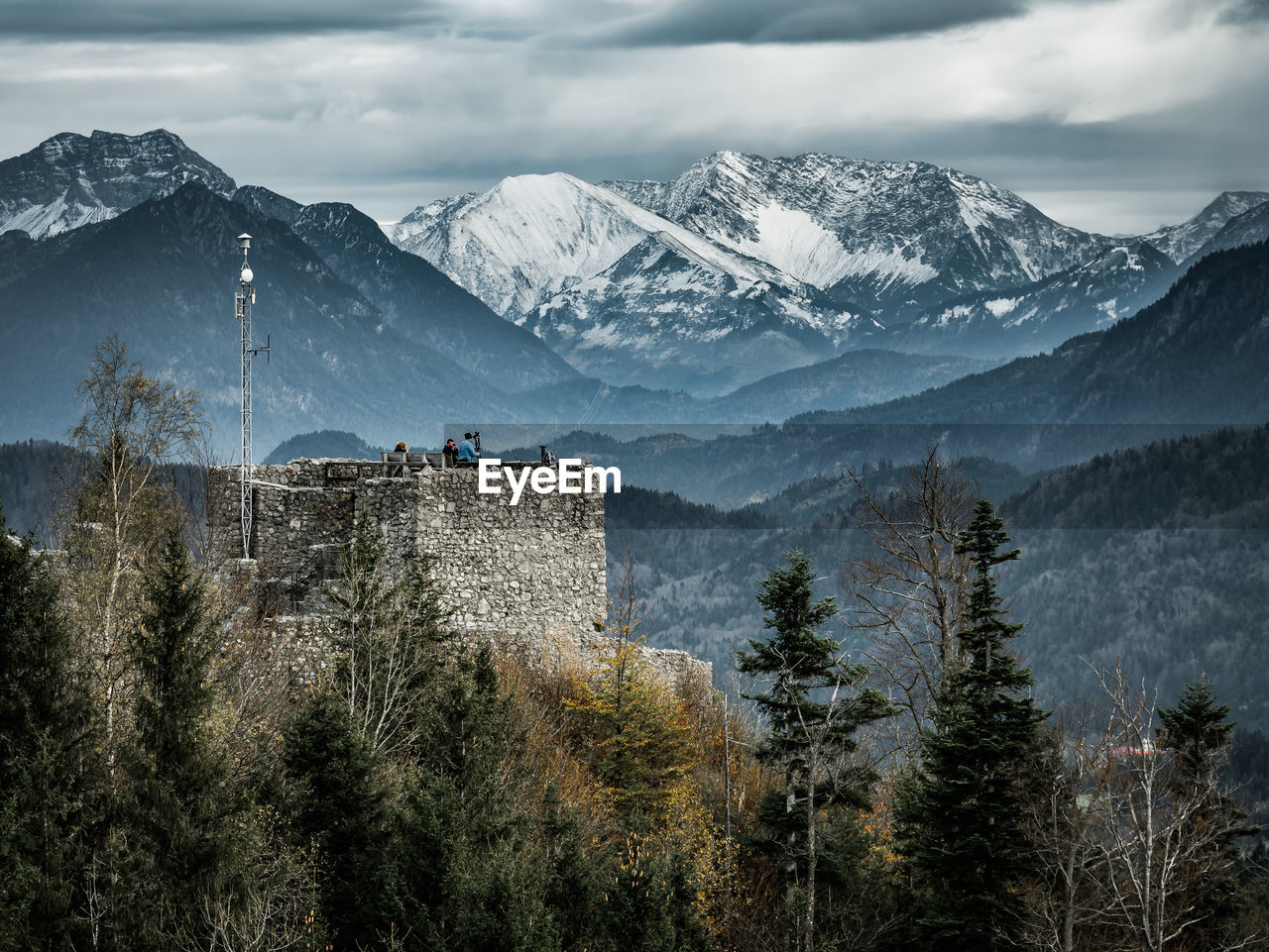 Castle against snowcapped mountains during foggy weather