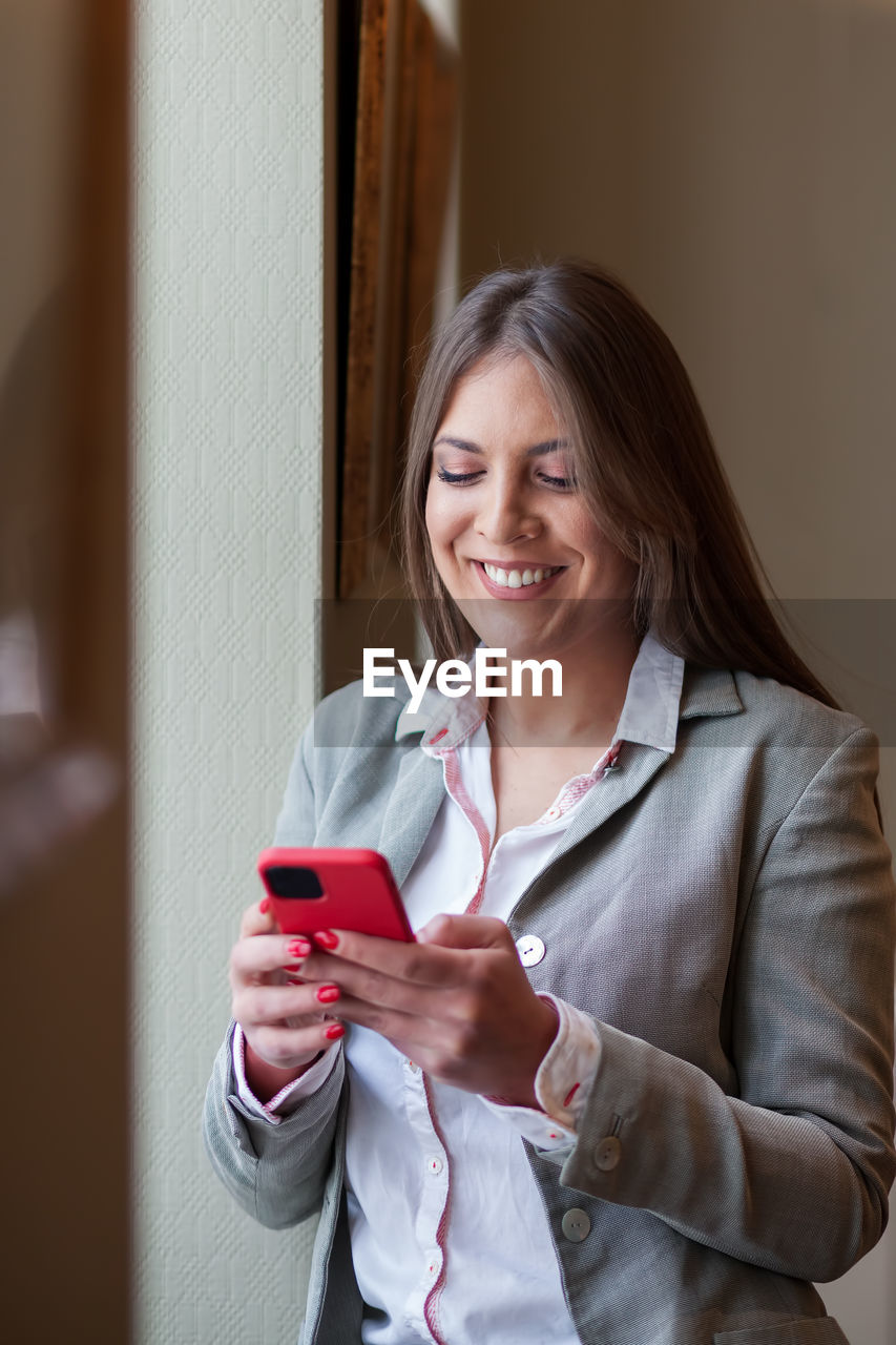 PORTRAIT OF SMILING WOMAN HOLDING MOBILE PHONE