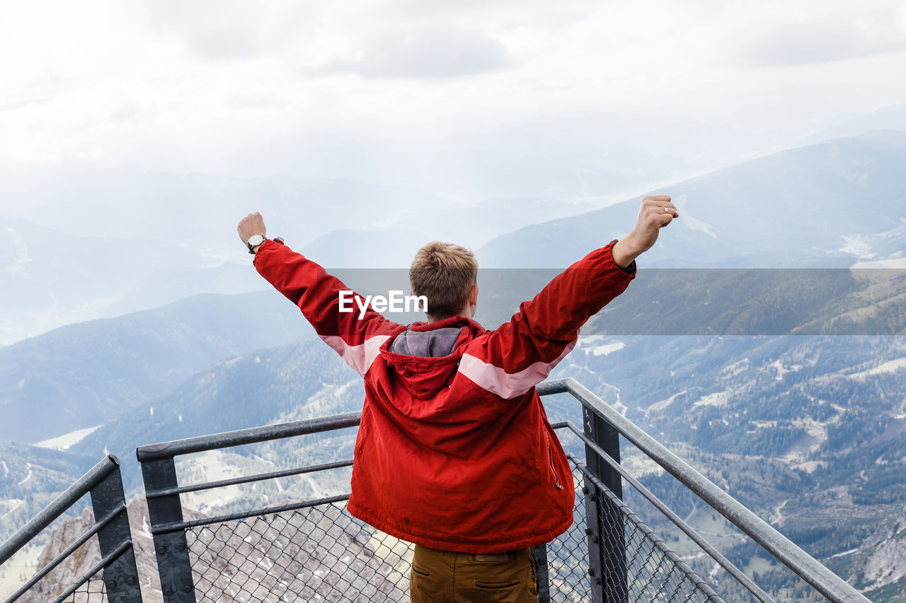 Millennial guy enjoys mountain views of alps from observation deck