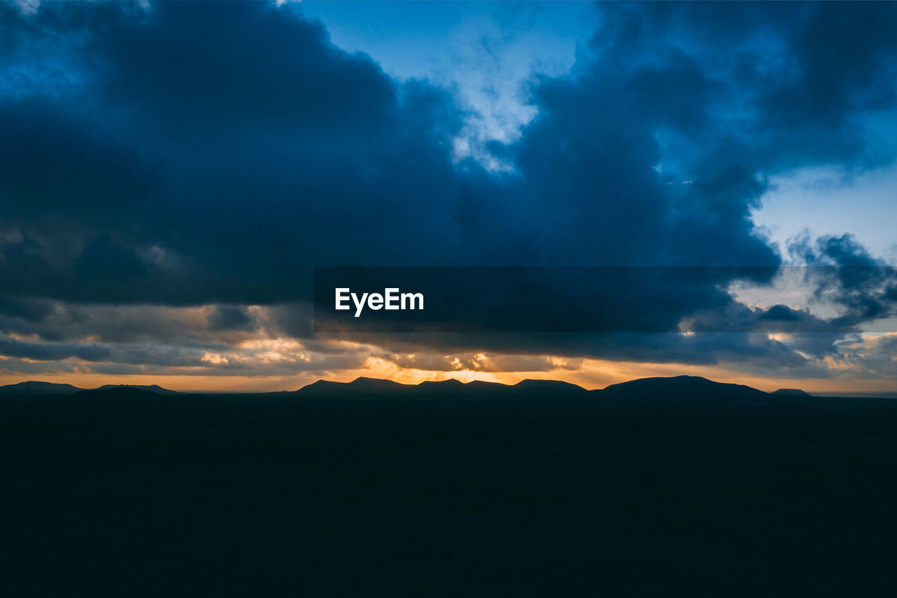 SCENIC VIEW OF DRAMATIC SKY OVER SILHOUETTE MOUNTAINS