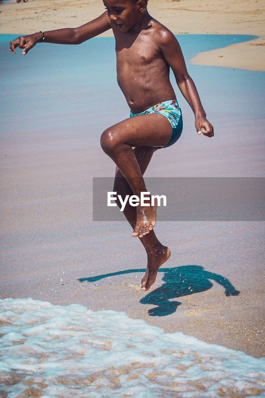 Full length of boy enjoying on shore at beach