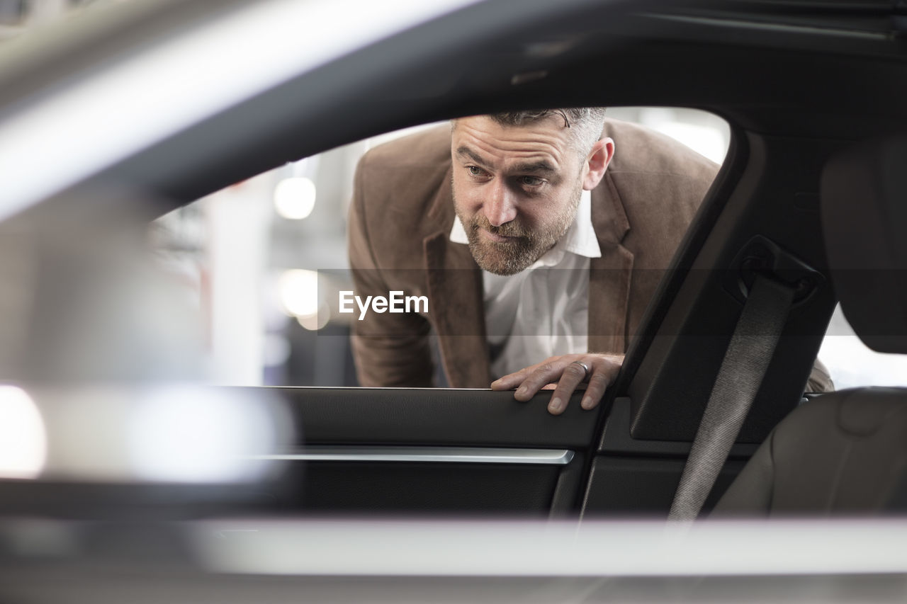 Man looking into car in car dealership