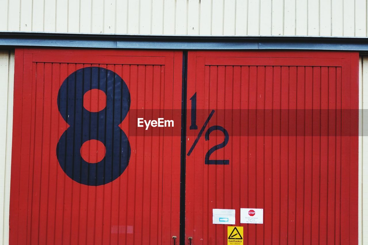 Low angle view of numbers on red metallic door
