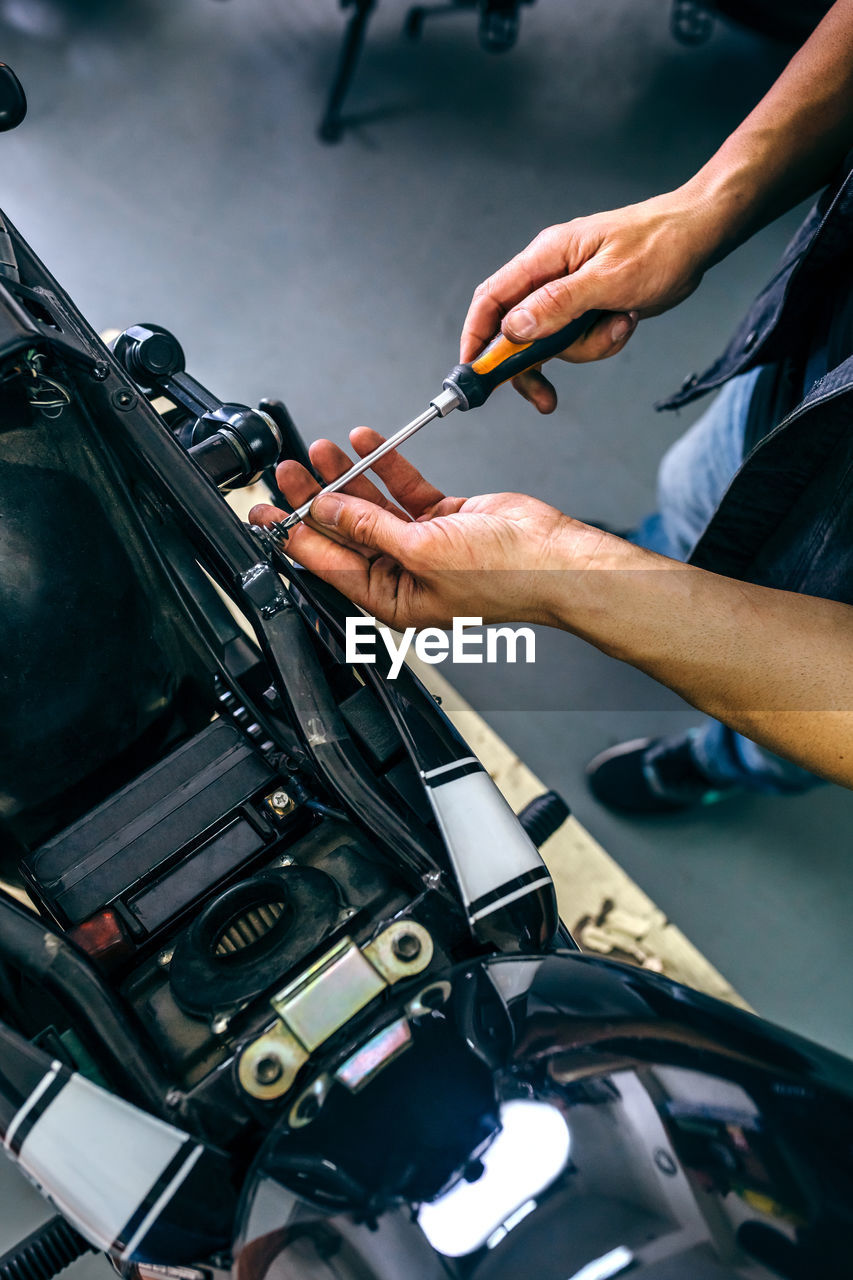 Low section of mature mechanic repairing motorcycle in garage