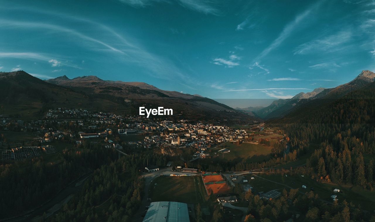 Aerial view of townscape by mountains against sky