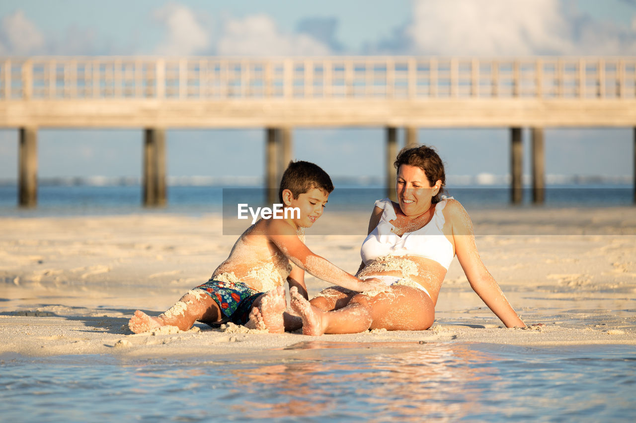 Mother and son covering each other in mud on the beach