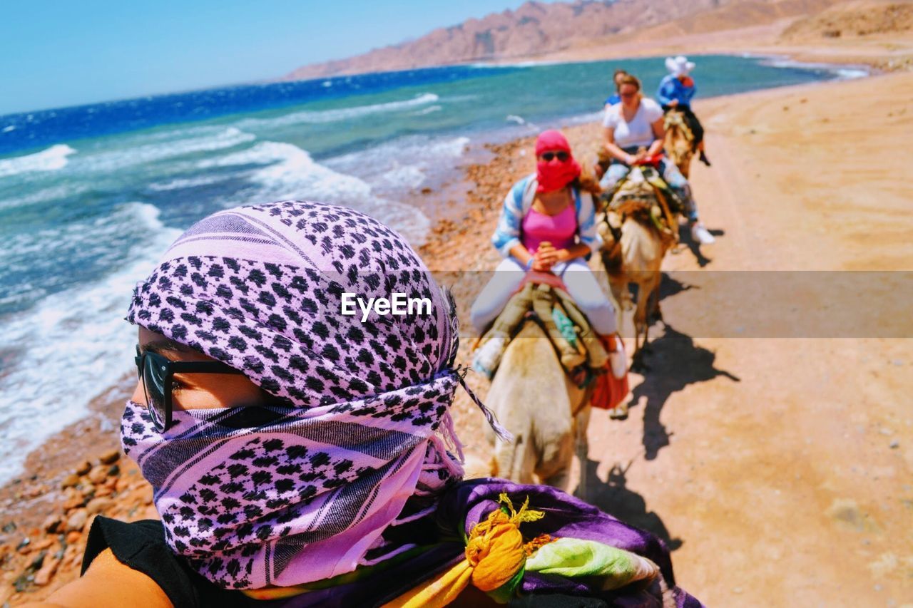 Women riding camels at beach