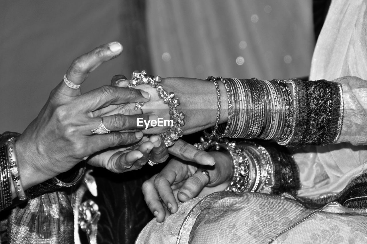 Close-up of bridesmaid helping bride wear bangle