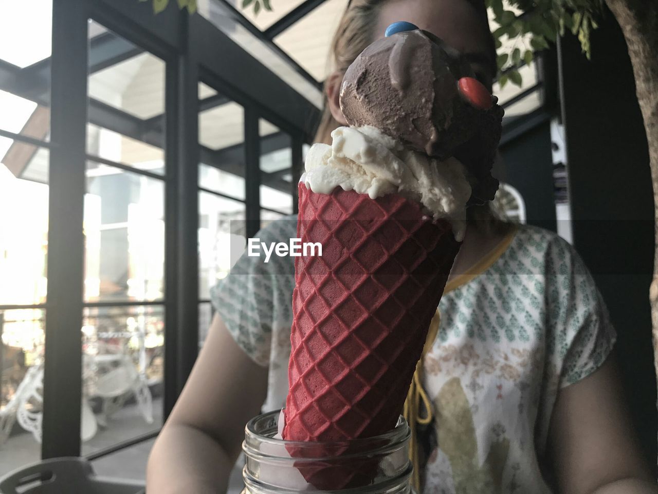 Close-up of fresh ice cream against woman at cafe