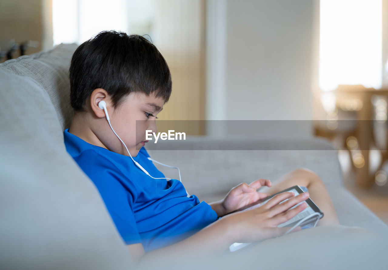 Rear view of boy using mobile phone