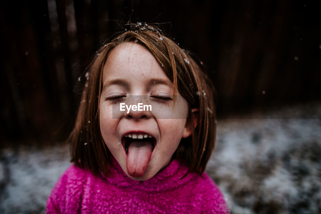 Young girl trying to catch snow flakes on her tongue in winter