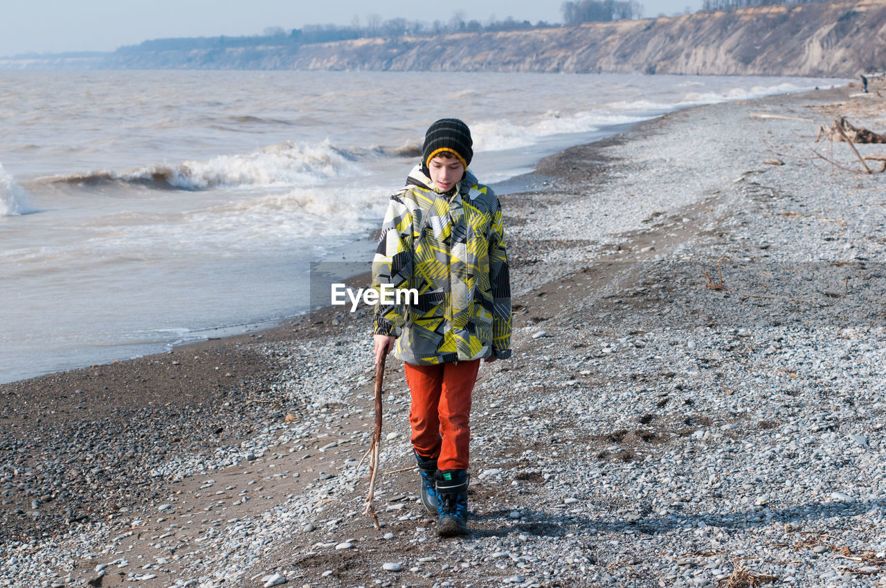 Front view of boy walking on beach