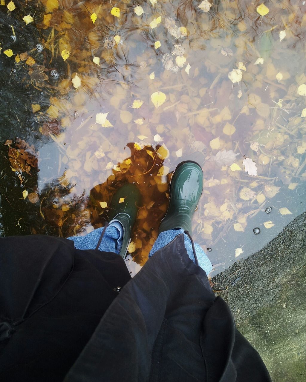 Low section of person standing on puddle during autumn