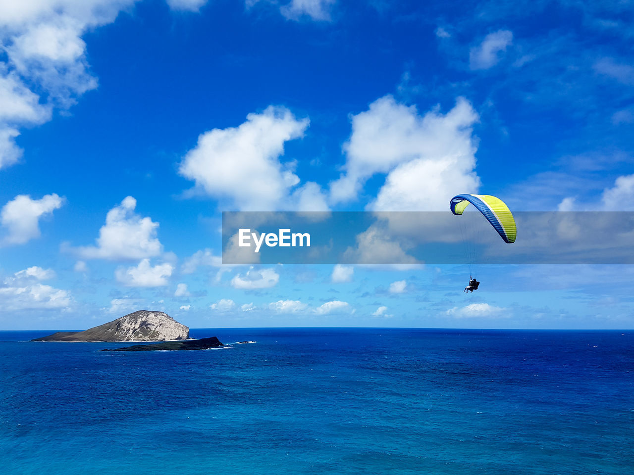 PERSON PARAGLIDING OVER SEA AGAINST SKY