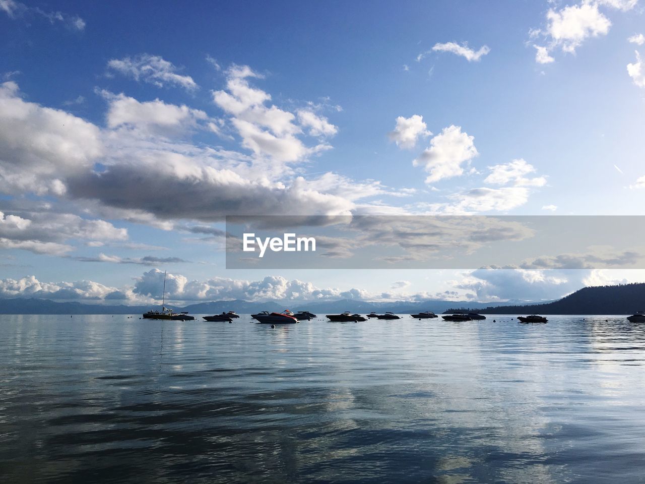 Boats in sea against cloudy sky