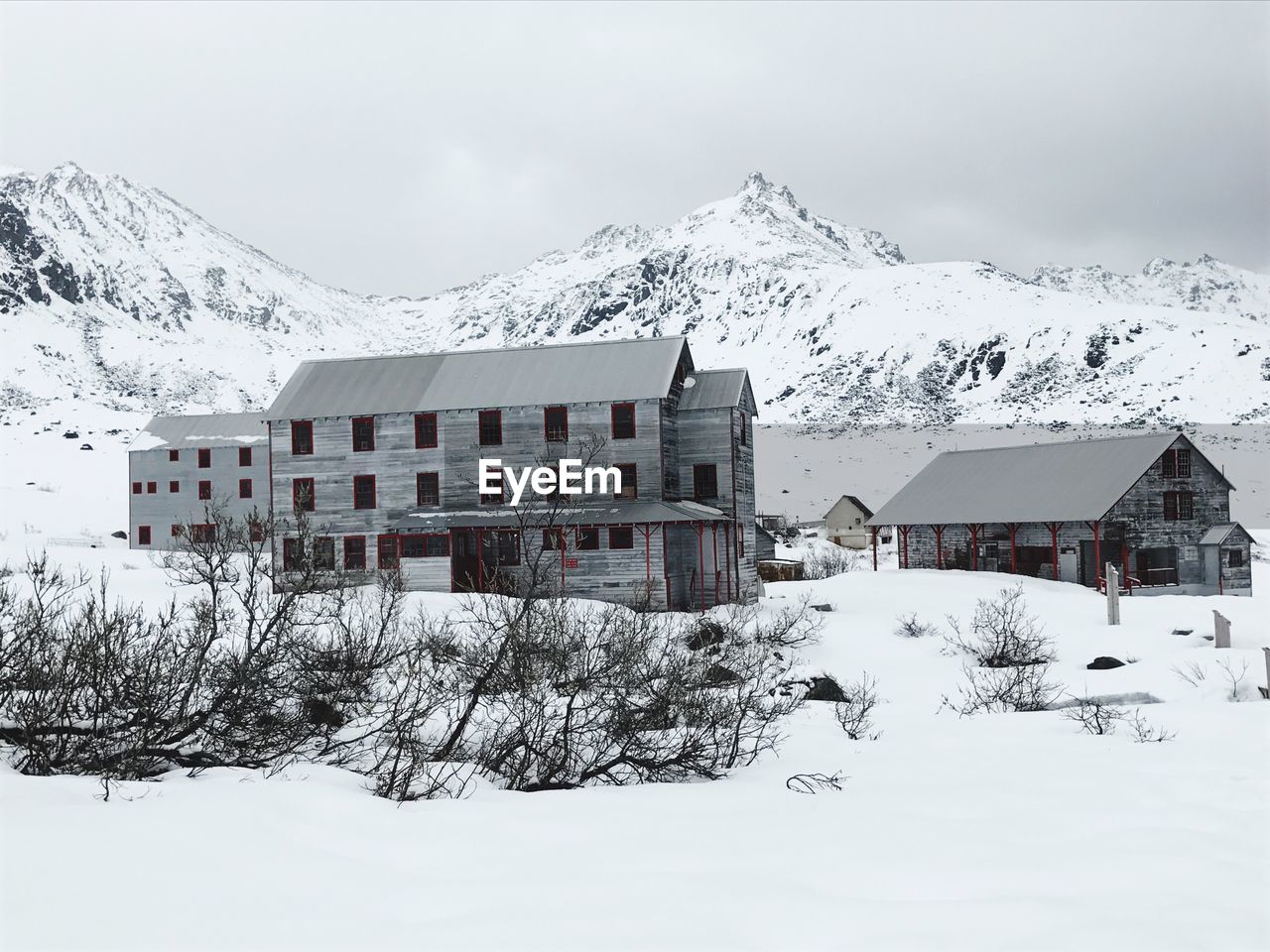 HOUSES BY SNOWCAPPED MOUNTAINS AGAINST SKY