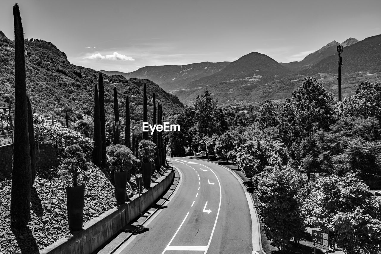 road, mountain, transportation, nature, black and white, symbol, sky, tree, plant, monochrome, mountain range, sign, monochrome photography, scenics - nature, no people, the way forward, landscape, road marking, beauty in nature, marking, travel, environment, outdoors, day, black, travel destinations, city, architecture, street, tranquil scene, tranquility, land, infrastructure