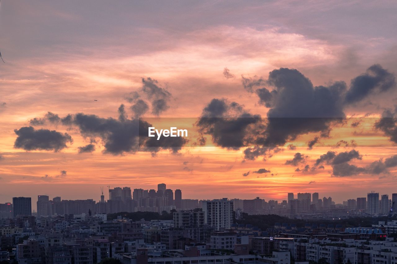 Scenic view of dramatic sky over city during sunset