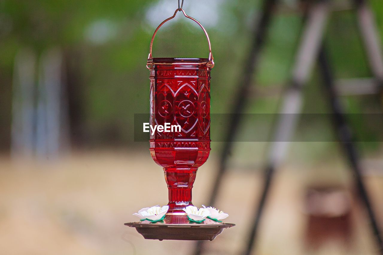 CLOSE-UP OF RED BELL HANGING ON METAL STRUCTURE IN CONTAINER