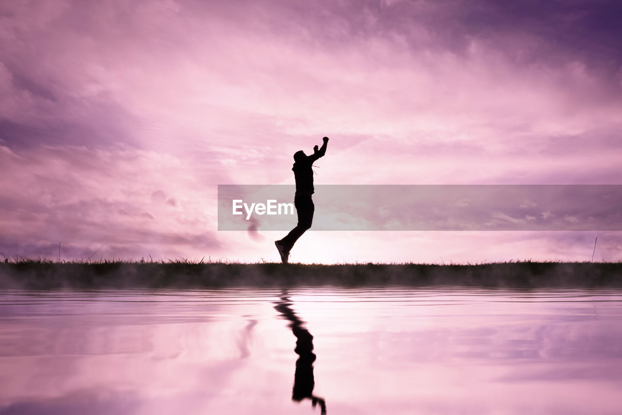 water, reflection, sky, cloud, silhouette, lake, one person, nature, morning, adult, beauty in nature, dusk, tranquility, full length, sunrise, horizon, pink, arm, lifestyles, tranquil scene, men, scenics - nature, balance, sports, vitality, outdoors, side view, limb, idyllic, leisure activity, activity, human limb, exercising